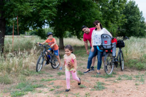 Paseos en familia, la fase más importante familia en un paseo en el campo, niño en bicicleta con su hermana pequeña corriendo junto a su madre y padre